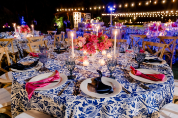 Blue and white Greek island–inspired welcome dinner table setting with floral centerpiece and candlelight at the Welcome Night celebration

