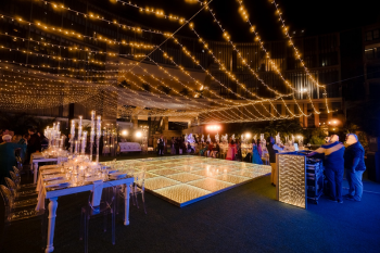 Sangeet night decor setup with illuminated LED dance floor, string lights overhead, and elegant table settings at an Indian destination wedding celebration
