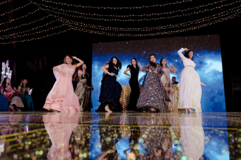 Ummae dancing with friends during a choreographed sangeet performance at an Indian destination wedding with LED dance floor and string lights overhead