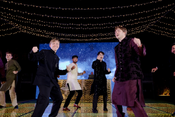 Ryan dancing with friends during a sangeet performance at an Indian destination wedding under string lights and LED dance floor.