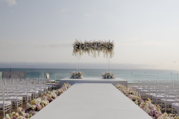 Oceanfront Indian wedding mandap with white aisle and pastel floral arrangements overlooking the sea
