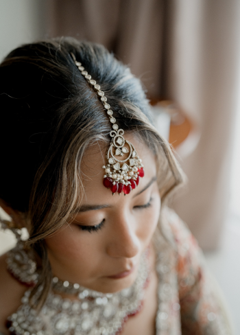 Close-up of bride wearing traditional Indian bridal jewelry and soft glam makeup while getting ready for a destination wedding.