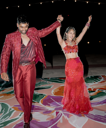 Bride and groom dancing at a sangeet celebration on a colorful dance floor with string lights during an Indian destination wedding.