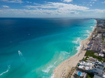 Aerial view of Mexico’s coastline with turquoise Caribbean waters, white sand beaches, and resort-lined shoreline in Cancun and Riviera Maya.