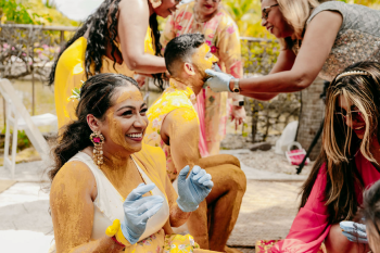 Malena and Eshwar laughing during their vibrant outdoor haldi ceremony with family and friends