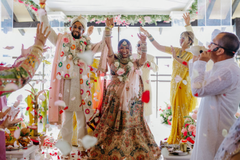 Malena and Eshwar celebrating the end of their Hindu wedding ceremony as guests tossed flower petals