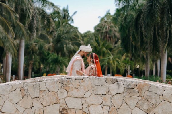 Indian bride and groom sharing a romantic moment on a stone bridge during their destination wedding at Generations Riviera Maya in Mexico