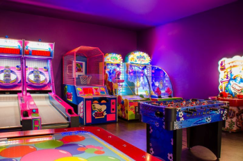 Colorful indoor kids club arcade with basketball games, air hockey, and interactive machines designed for children and teens