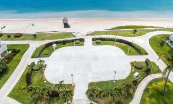 Open-air terrace venue with large paved event space, landscaped greenery, and ocean views near the beach