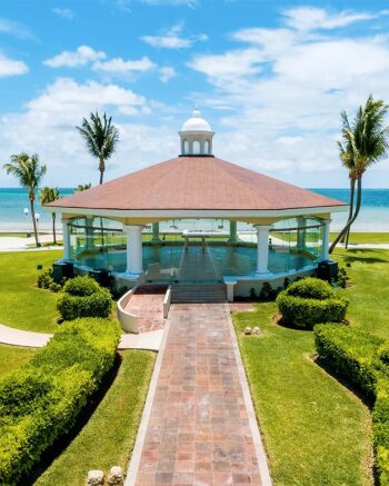 Oceanfront gazebo with white columns and a domed roof set along a landscaped path overlooking the beach