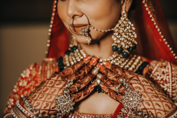 Close-up of an Indian bride wearing traditional jewelry, bridal attire, and intricate mehndi on her hands