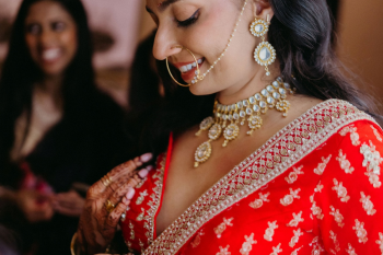 Close-up of Katherine wearing traditional
bridal jewelry, mehndi, and elegant wedding makeup before her ceremony.