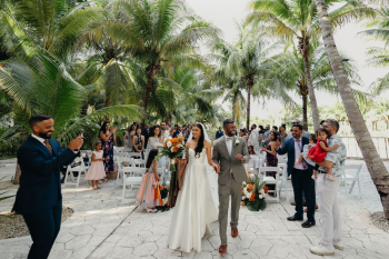 Katherine and Marun walk back down the
aisle together after their Christian wedding ceremony beneath the palms.