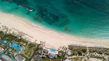 Aerial view of Punta Cana beach resorts with palm trees, clear water, and wide sandy coastline