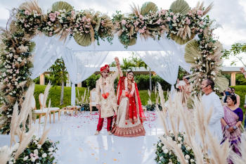 Palak and Neel celebrating during their Indian wedding ceremony under a floral mandap at Moon Palace The Grand Cancun