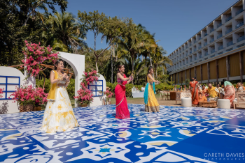 Sangeet celebration on a decorative blue and white patterned dance floor at Dreams Bahia Mita, with guests in colorful traditional outfits dancing outdoors surrounded by tropical landscaping. Sangeet celebration on a decorative blue and white patterned dance floor at Dreams Bahia Mita, with guests in colorful traditional outfits dancing outdoors surrounded by tropical landscaping.