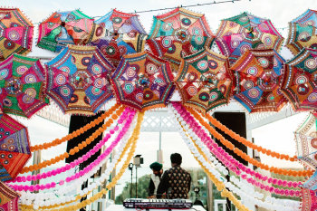 A DJ sets up under a canopy of embroidered umbrellas and marigold garlands at a South Asian destination wedding, one of the vendors couples need to book early. A DJ sets up under a canopy of embroidered umbrellas and marigold garlands at a South Asian destination wedding, one of the vendors couples need to book early.