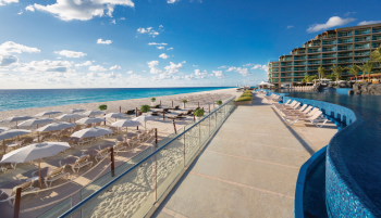 Beachfront view at Hard Rock Hotel Cancun with lounge chairs, ocean shoreline, and poolside walkway Beachfront view at Hard Rock Hotel Cancun with lounge chairs, ocean shoreline, and poolside walkway
