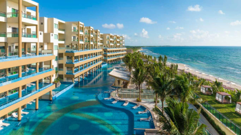 Beachfront view of Generations Riviera Maya with oceanfront suites, pool terraces, and palm-lined shoreline Beachfront view of Generations Riviera Maya with oceanfront suites, pool terraces, and palm-lined shoreline