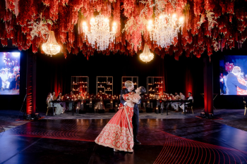 Ummae and Ryan share their first dance at their Indian destination wedding at Dreams Bahia Mita and Secrets Bahia Mita, surrounded by dramatic red, black, and white décor, crystal chandeliers, and an elaborate floral installation suspended above the dance floor. Ummae and Ryan share their first dance at their Indian destination wedding at Dreams Bahia Mita and Secrets Bahia Mita, surrounded by dramatic red, black, and white décor, crystal chandeliers, and an elaborate floral installation suspended above the dance floor.