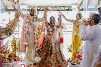 Indian bride and groom celebrating at wedding ceremony with flower petal toss at Pier Deck venue, Generations Riviera Maya, Mexico