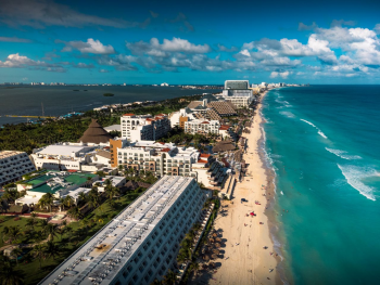 Aerial view of Cancun's Hotel Zone with beachfront all-inclusive resorts along the Caribbean coastline, one of the most popular destinations for Indian destination weddings in Mexico. Aerial view of Cancun's Hotel Zone with beachfront all-inclusive resorts along the Caribbean coastline, one of the most popular destinations for Indian destination weddings in Mexico.