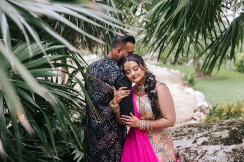 South Asian destination wedding couple in Sangeet outfits at a Cancun resort surrounded by palm trees South Asian destination wedding couple in Sangeet outfits at a Cancun resort surrounded by palm trees