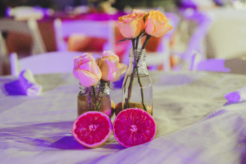 Wedding tablescape with rose stems in glass bottles and halved blood oranges instead of a more traditional centerpiece Wedding tablescape with rose stems in glass bottles and halved blood oranges instead of a more traditional centerpiece