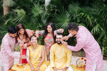 Guests applying haldi paste to a bride and groom at an outdoor Indian wedding Haldi ceremony Guests applying haldi paste to a bride and groom at an outdoor Indian wedding Haldi ceremony
