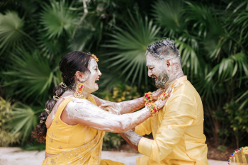 Bride and groom laughing together covered in haldi paste at an Indian wedding ceremony Bride and groom laughing together covered in haldi paste at an Indian wedding ceremony