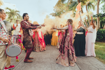 The couple dances together during their Baraat procession outside surrounded by colorful smoke bombs and cheering guests before moving to their indoor Indian wedding Sangeet in a ballroom The couple dances together during their Baraat procession outside surrounded by colorful smoke bombs and cheering guests before moving to their indoor Indian wedding Sangeet in a ballroom