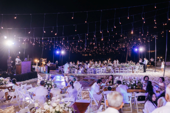 Beach wedding celebration at night with LED dance floor, string lights hanging above and white floral centerpieces. Beach wedding celebration at night with LED dance floor, string lights hanging above and white floral centerpieces.