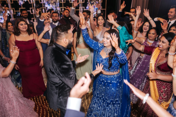 Bride and groom dancing at an Indian wedding reception with royal blue and gold decor Bride and groom dancing at an Indian wedding reception with royal blue and gold decor