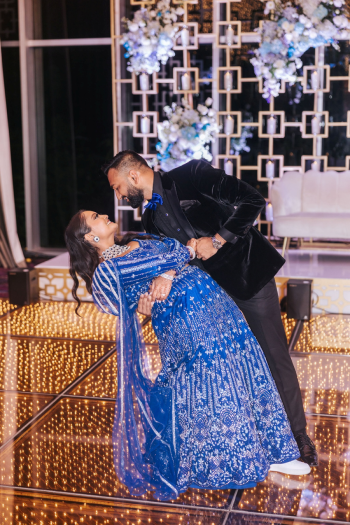 Bride and groom dancing in front of gold trellis reception stage backdrop with pale blue florals at an Indian wedding Bride and groom dancing in front of gold trellis reception stage backdrop with pale blue florals at an Indian wedding