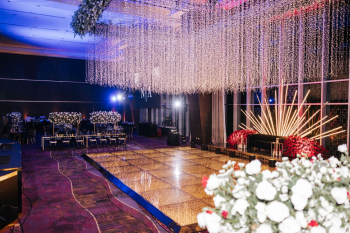 Black and gold ballroom reception stage with red floral installations at an Indian wedding Black and gold ballroom reception stage with red floral installations at an Indian wedding