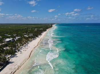 Aerial view of the Riviera Maya coastline near Tulum, showing white sand beaches bordered by jungle and turquoise water Aerial view of the Riviera Maya coastline near Tulum, showing white sand beaches bordered by jungle and turquoise water