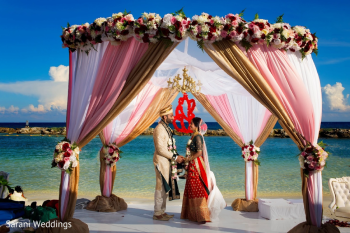 Indian bride and groom Gopi and Ronak exchange vows under a floral mandap at their oceanfront wedding ceremony at Hard Rock Riviera Maya Indian bride and groom Gopi and Ronak exchange vows under a floral mandap at their oceanfront wedding ceremony at Hard Rock Riviera Maya