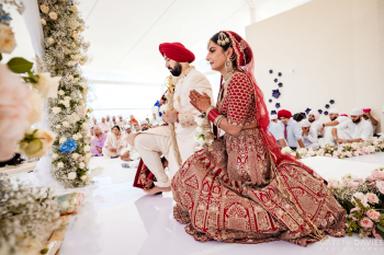 Sikh groom in a red turban and kirpan seated beside his bride during their Anand Karaj ceremony at Planet Hollywood Cancun, with guests' heads covered per tradition Sikh groom in a red turban and kirpan seated beside his bride during their Anand Karaj ceremony at Planet Hollywood Cancun, with guests' heads covered per tradition