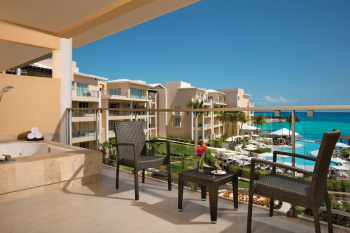 Private balcony of a Preferred Club Ocean Suite at Dreams Jade Resort and Spa, with a whirlpool tub, seating area, and views of the pools and Caribbean Sea. Private balcony of a Preferred Club Ocean Suite at Dreams Jade Resort and Spa, with a whirlpool tub, seating area, and views of the pools and Caribbean Sea.